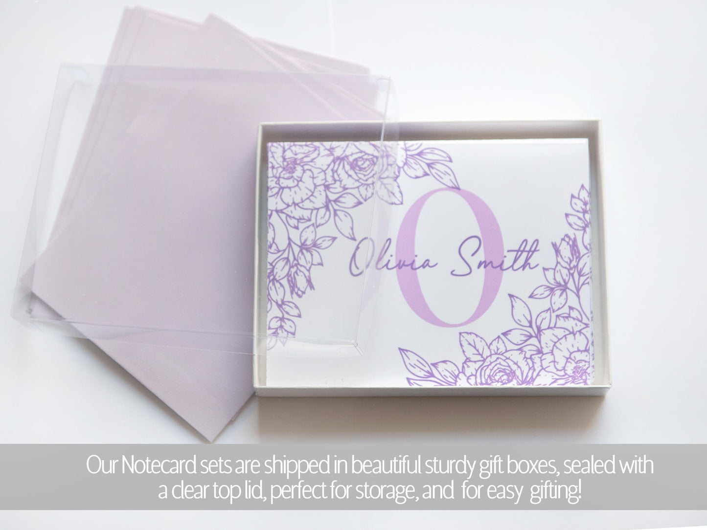 A set of purple floral-designed greeting cards with the name "Olivia Smith" printed on them, placed inside a clear gift box.