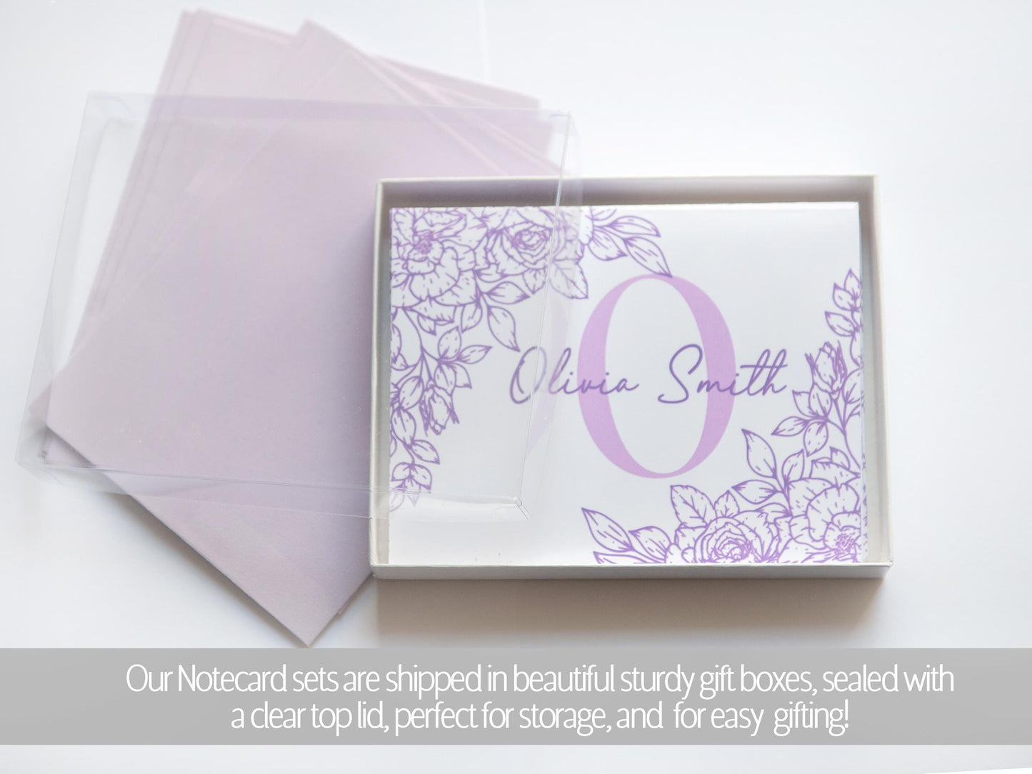 A set of purple floral-designed greeting cards with the name "Olivia Smith" printed on them, placed inside a clear gift box.